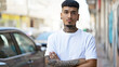 © Krakenimages.com - Cool young latin man with tattooed arms, standing outdoors on the urban street, carrying a relaxed yet serious expression with his arms casually crossed under the sunny city skyline.