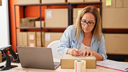 Canvas Print - Middle age hispanic woman ecommerce business worker writing on package at office