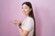 © Krakenimages.com - Chinese young woman standing over pink background pointing aside with hands open palms showing copy space, presenting advertisement smiling excited happy