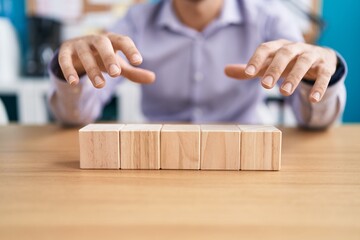 Sticker - Young hispanic man business worker sitting on table with wooden cubes at office