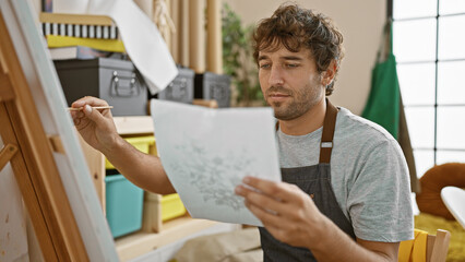 Canvas Print - Young man artist looking at draw on paper drawing at art studio