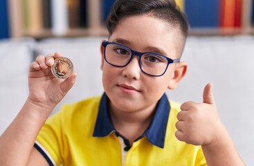 Poster - Young hispanic kid holding tron cryptocurrency coin smiling happy and positive, thumb up doing excellent and approval sign