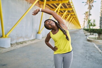 Sticker - African american woman wearing sportswear stretching arm at street