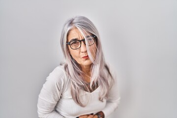 Wall Mural - Middle age woman with grey hair standing over white background with hand on stomach because indigestion, painful illness feeling unwell. ache concept.