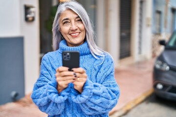 Poster - Middle age grey-haired woman smiling confident using smartphone at street