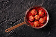 Meatballs. Beef meat balls, shot from above in a pan, with parsley and tomato sauce, on a black slate background