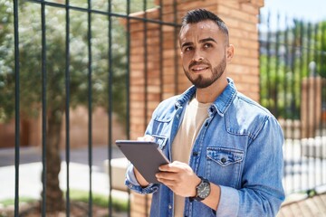 Canvas Print - Young hispanic man smiling confident using touchpad at street