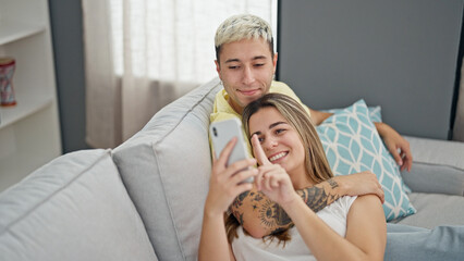 Poster - Beautiful couple using smartphone smiling at home