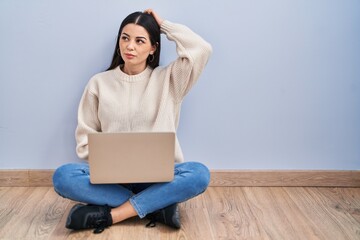 Wall Mural - Young woman using laptop sitting on the floor at home confuse and wondering about question. uncertain with doubt, thinking with hand on head. pensive concept.