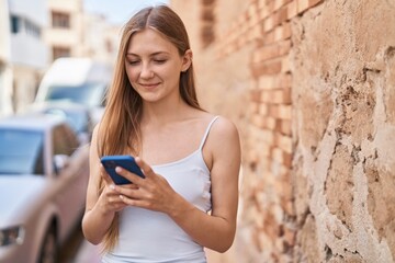 Canvas Print - Young caucasian woman smiling confident using smartphone at street