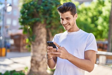 Sticker - Young hispanic man smiling confident using smartphone at park