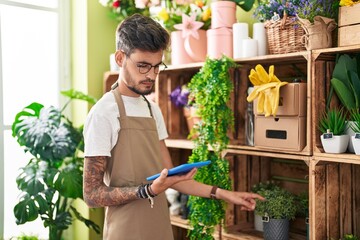 Poster - Young hispanic man florist using touchpad with serious expression at flower shop