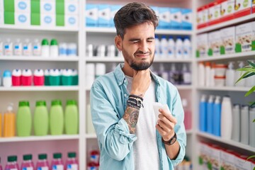 Wall Mural - Young hispanic man customer touching throat holding napkin at pharmacy