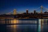 Fototapeta  - Classic panoramic view of famous Oakland Bay Bridge with the skyline of San Francisco in the background illuminated in beautiful twilight after sunset in summer, California, USA