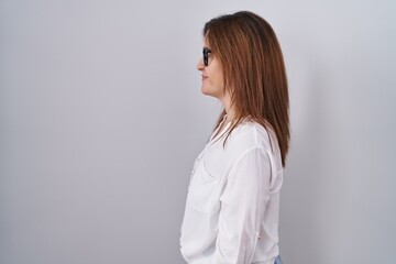 Poster - Brunette woman standing over white isolated background looking to side, relax profile pose with natural face and confident smile.