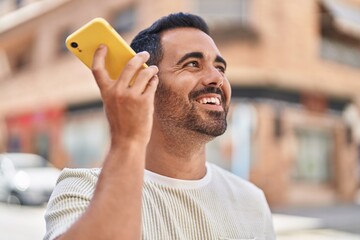 Sticker - Young hispanic man smiling confident listening audio message by the smartphone at street