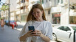 © Krakenimages.com - Young blonde woman using smartphone smiling at street