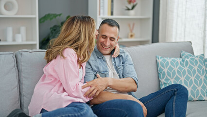 Poster - Man and woman couple hugging each other sitting on sofa at home