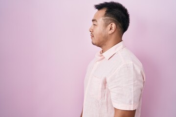 Sticker - Chinese young man standing over pink background looking to side, relax profile pose with natural face and confident smile.