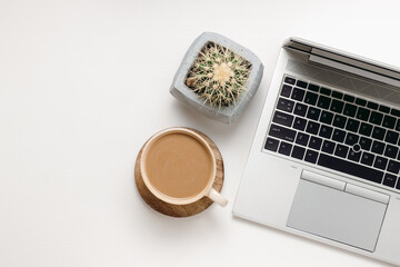 Office desk table with copy space for branding, business and design. Workspace with laptop, coffee and cactus in pot on white wooden table. Home office, aesthetic style, top view.