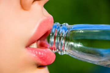 Beautiful female lips, bottle with soda. Close-up of a girl with a bottle. Natural makeup, full lip. Cute fashion summer look with bottle of water. Closeup of woman's lips drinking