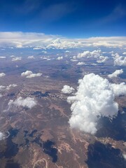 Canvas Print - Vertical aerial view of a rural landscape enveloped in puffy clouds in blue sky background