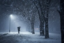 Person With Umbrella Walking In Snowstorm At Night