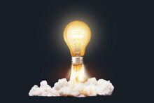 Creative Light Bulb Rocket With Blast And Clouds Takes Off On A Dark Background, Concept. Successful Launch Start Up, Creative Idea. Think Differently. Creative Generator. Smart And Thinking