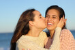 © PheelingsMedia - Happy woman kissing a friend on the cheek