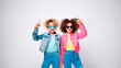 Dos niñas adolescentes Gen Z, vestidas a la moda, con gafas, señalando con su dedo, aisladas en un fondo blanco 