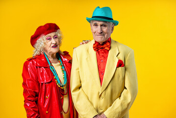 Wall Mural - Beautiful senior old couple wearing fancy party clothes acting in studio on a colored background. Conceptual image about third age and seniority, old people feeling young inside.