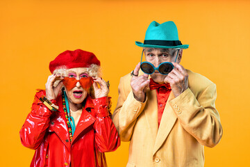 Wall Mural - Beautiful senior old couple wearing fancy party clothes acting in studio on a colored background. Conceptual image about third age and seniority, old people feeling young inside.