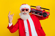 © deagreez - Photo of cool attractive santa dressed red suit tie enjoying boom box songs showing hard rock sign isolated yellow color background