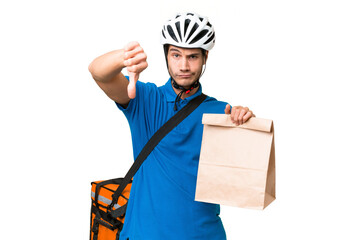 Wall Mural - Young caucasian man taking a bag of takeaway food over isolated background showing thumb down with negative expression