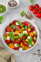 Wall Mural - Caprese salad with cherry tomatoes, mini mozzarella balls, avocado, pesto sauce and fresh basil. Healthy vegetarian meal.