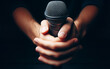 hand holding microphone on a black background The hands of a singer who is about to sing
