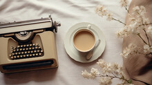  A Cup Of Coffee And An Old Fashioned Typewriter On A Bed With A Flowered Pillow And A Blanket.