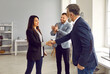 Business team showing professional recognition and work appreciation to a young female colleague. Happy young woman gets promoted and exchanges handshakes with her mature boss or senior manager