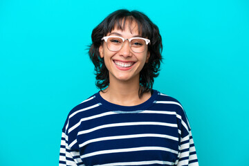 Wall Mural - Young Argentinian woman isolated on blue background With glasses with happy expression