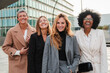 © Jose Calsina - Group of proud businesswomen smiling and looking at camera at workplace. Real executive women staring front, laughing together with suit and successful expression. Corporate female employees meeting