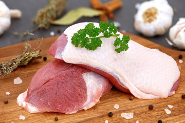 two raw duck breasts on wooden board with salt, pepper and other ingredients for preparing a delicous duck breast on holidays