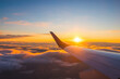 canvas print picture - Airplane flight in sunset sky over ocean water and wing of plane. View from the window of the Aircraft. Traveling in air.