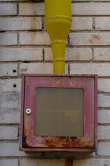 Wall Mural - Ivry-Sur-Seine, France - 09 27 2021: view of a rusty red and yellow box of an exterior alarm on a brick wall.