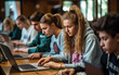 © piai - Teen students learning on laptop computers in ful modern classroom with wooden desks