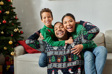 happy african american family in cozy sweaters hugging warmly and smiling at camera, Christmas