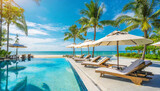 Fototapeta  - panoramic holiday landscape luxury beach poolside resort hotel swimming pool beach chairs beds umbrellas palm trees relax lifestyle blue sunny sky summer island seaside leisure travel vacation