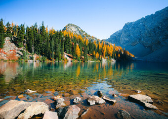 Picturesque view on Blue Lake. Autumn mountains landscape with Blue Lake and bright orange larches in the North Cascades National Park in Washington State, USA.	
