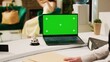 © DC Studio - Employee checking greenscreen template on laptop, working at reception counter in lobby to help guests. Front desk staff looking at chromakey display with isolated blank template, seaside resort.