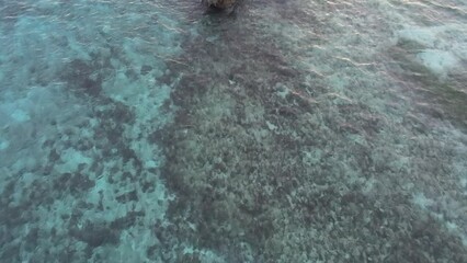 Wall Mural - Aerial view of a clear seawater with rock formation against a scenic sunset