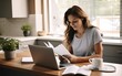 © piai - Smiling businesswoman reading financial document and using laptop on desk while working from home